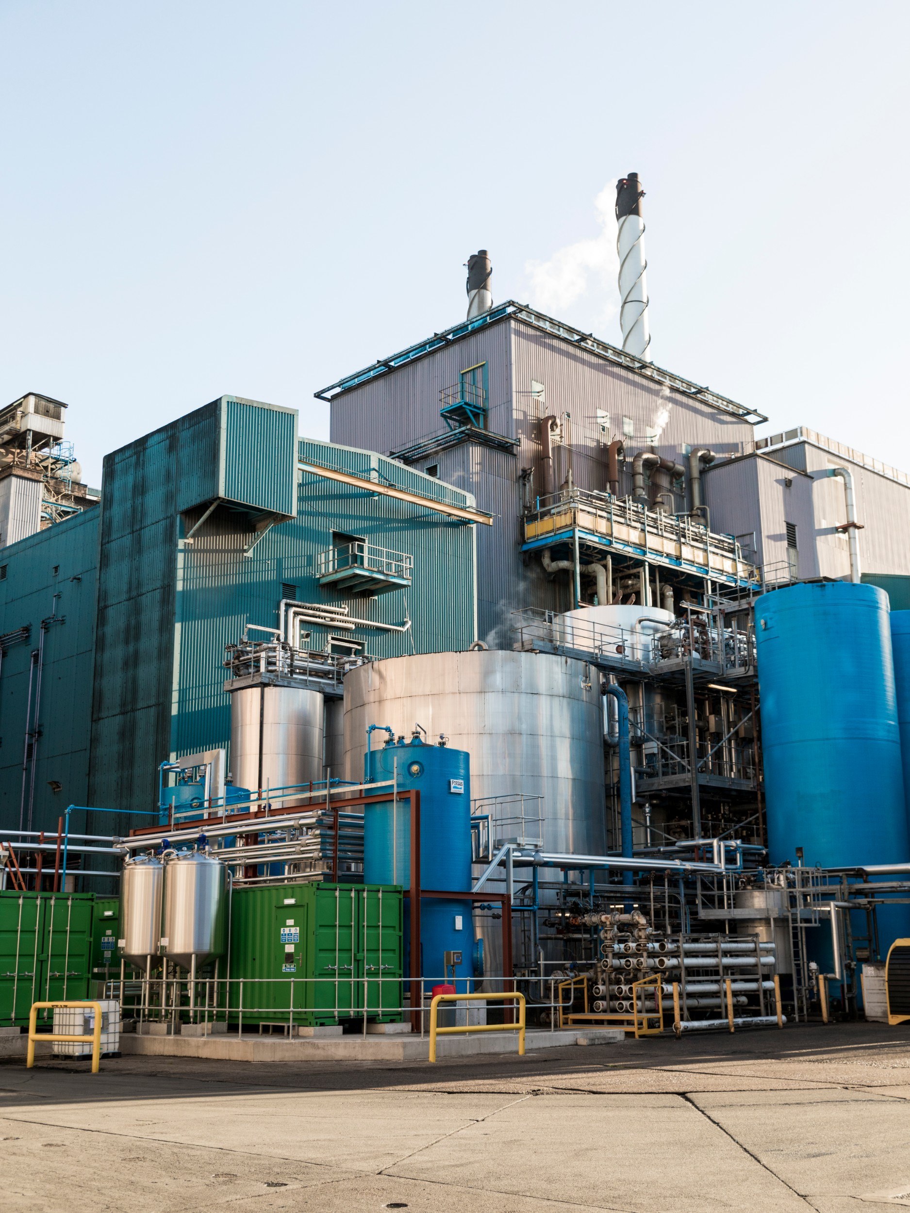 Exterior of a building that looks like a factory, with chimneys and cylindrical structures