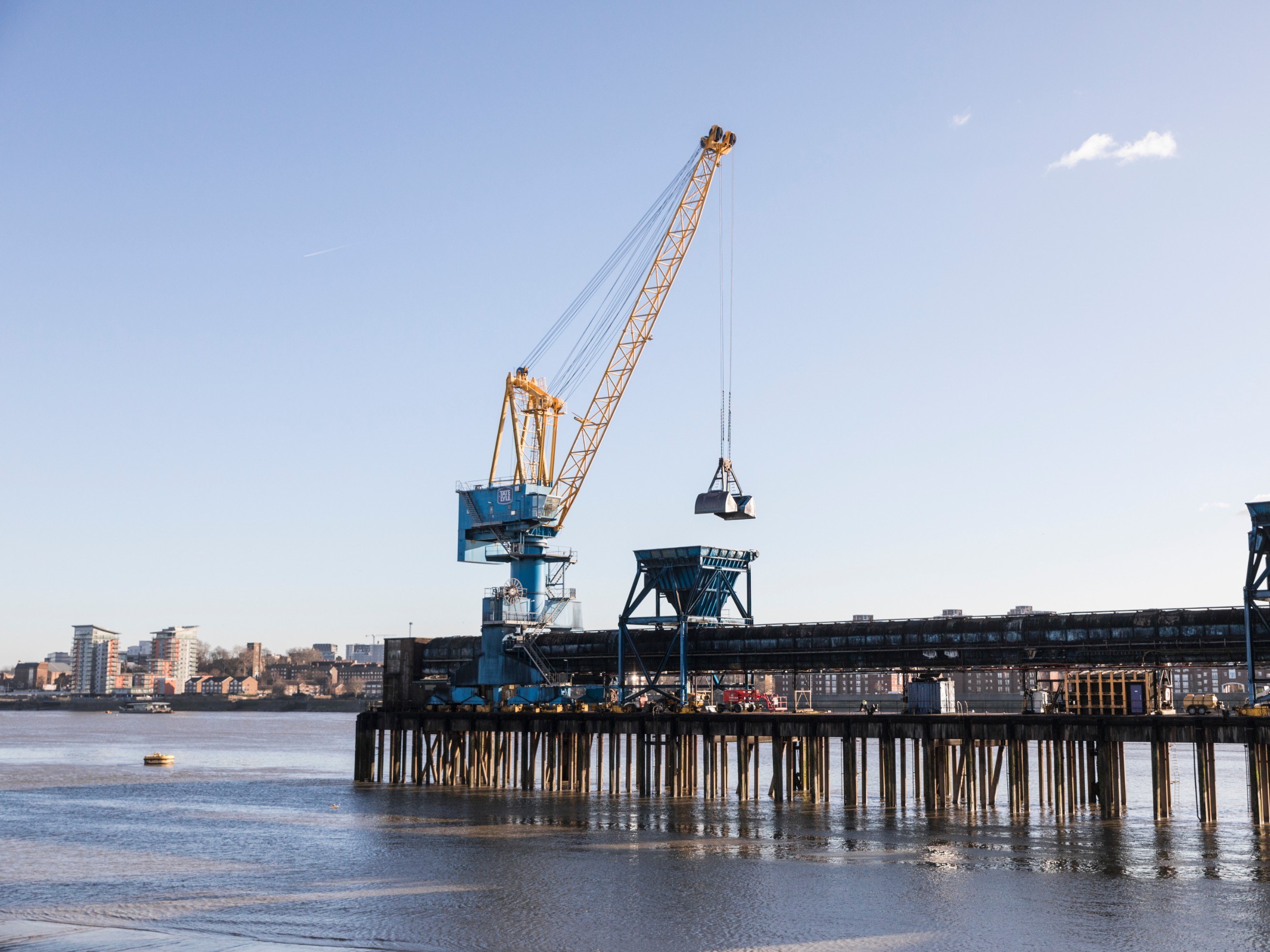 A pier jutting out into the river, with a crane on the end of it