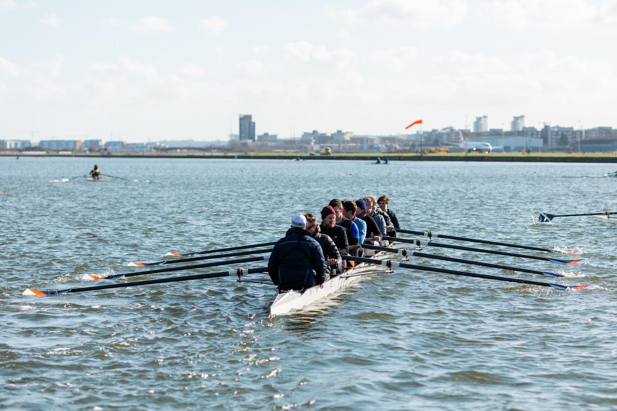 rowers on the water with the airport in the background