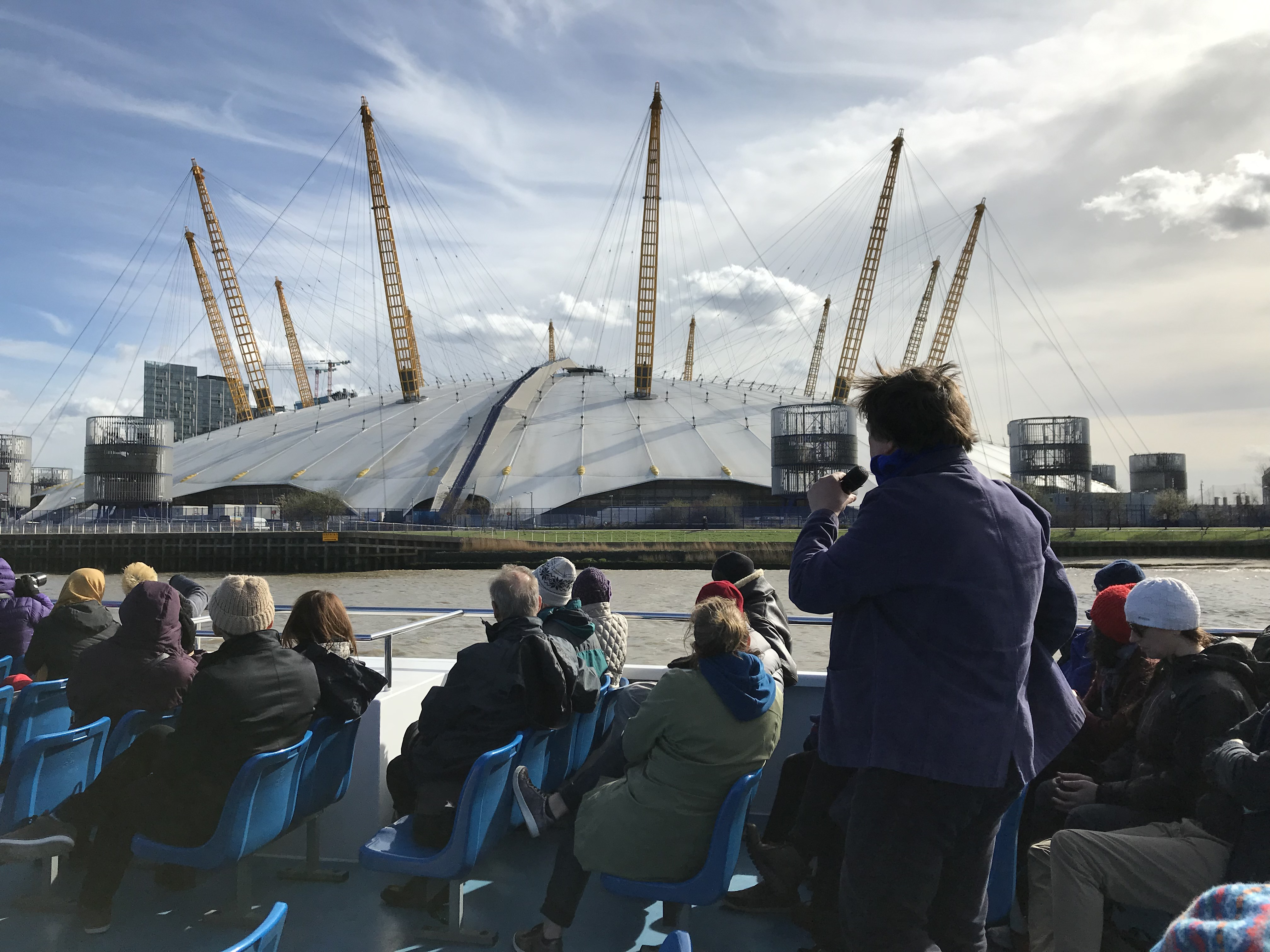 A crowd of people on the Thames East tour taking photos of The O2