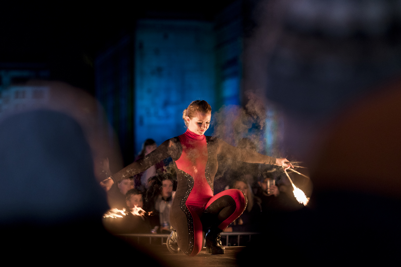 Dancer crouching down twirling sticks with fire on either end