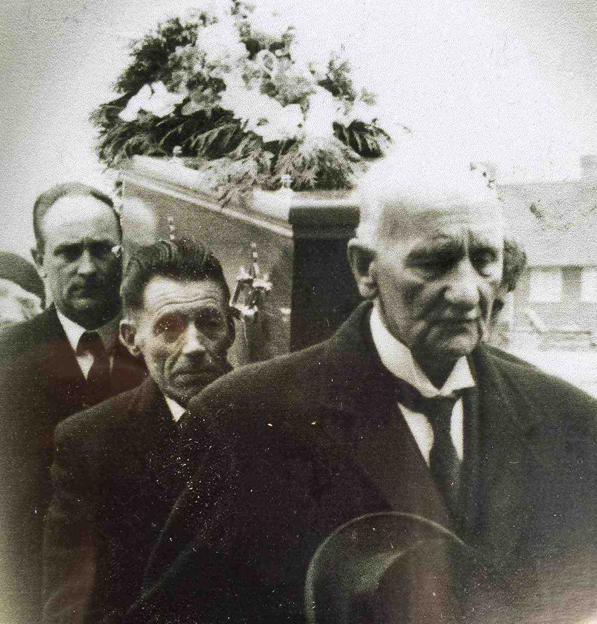 A photograph of three men carrying a coffin