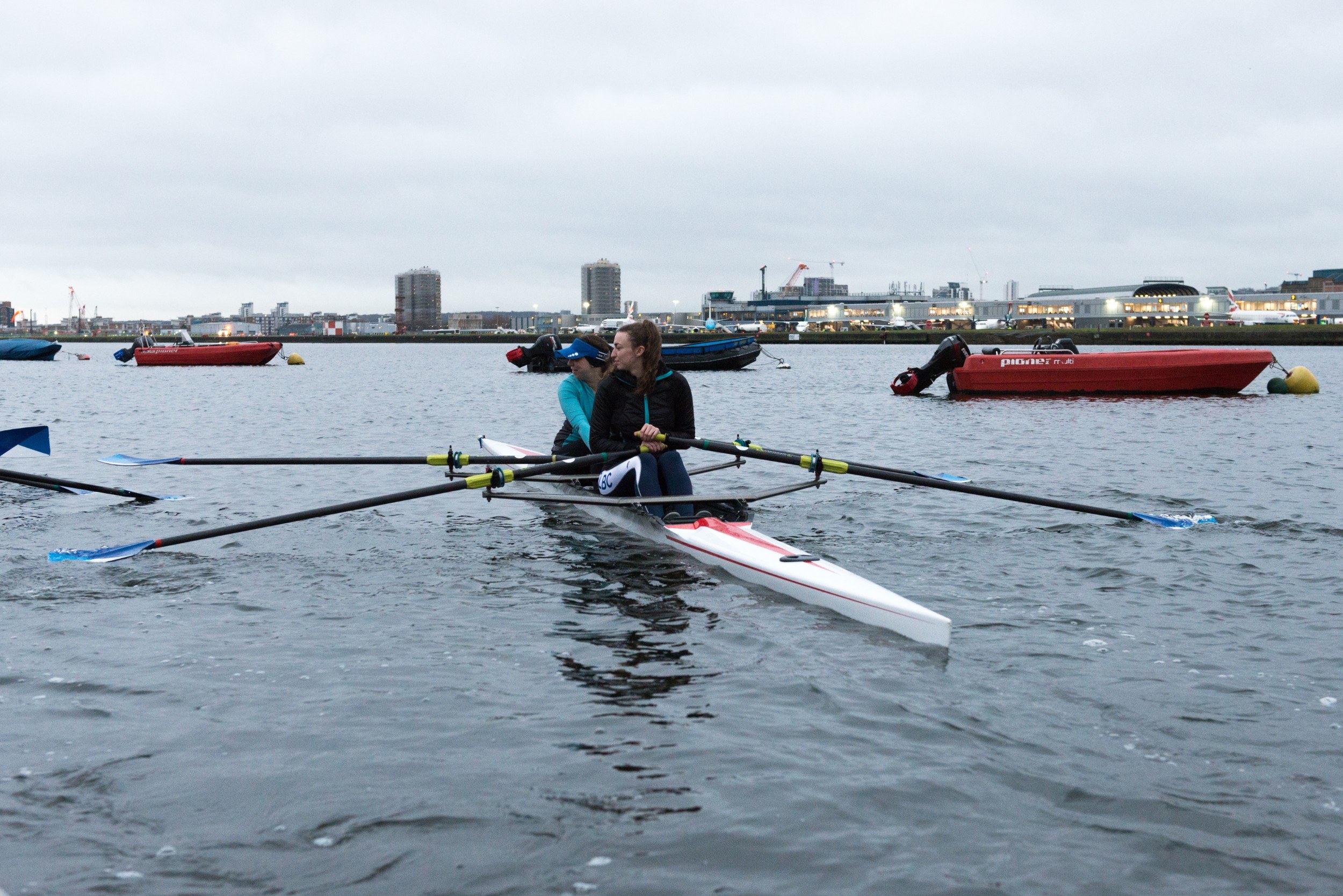 Two women rowing with other boats in the background
