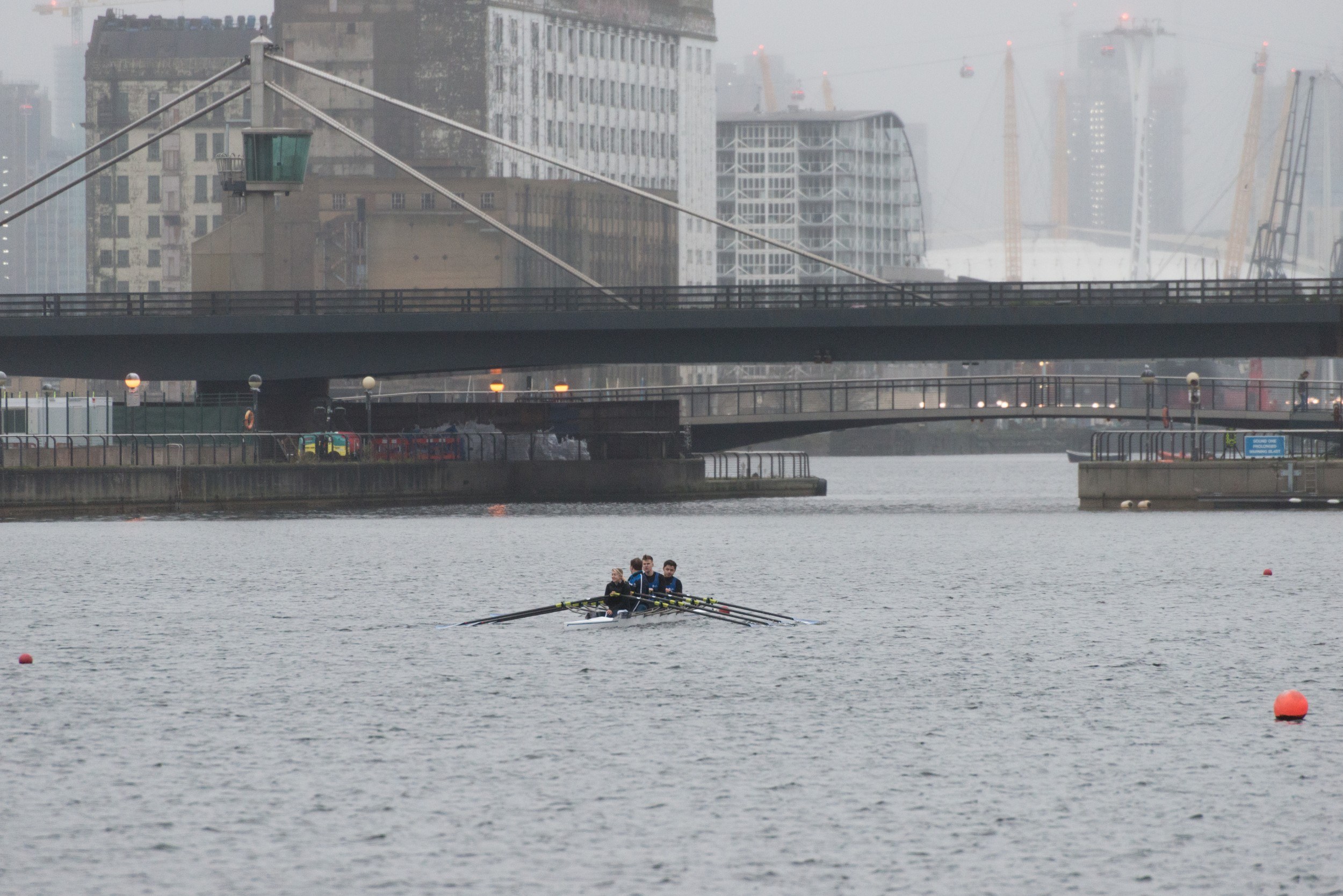 Scene of the docks with a rowing boat and the O2 visible in the background