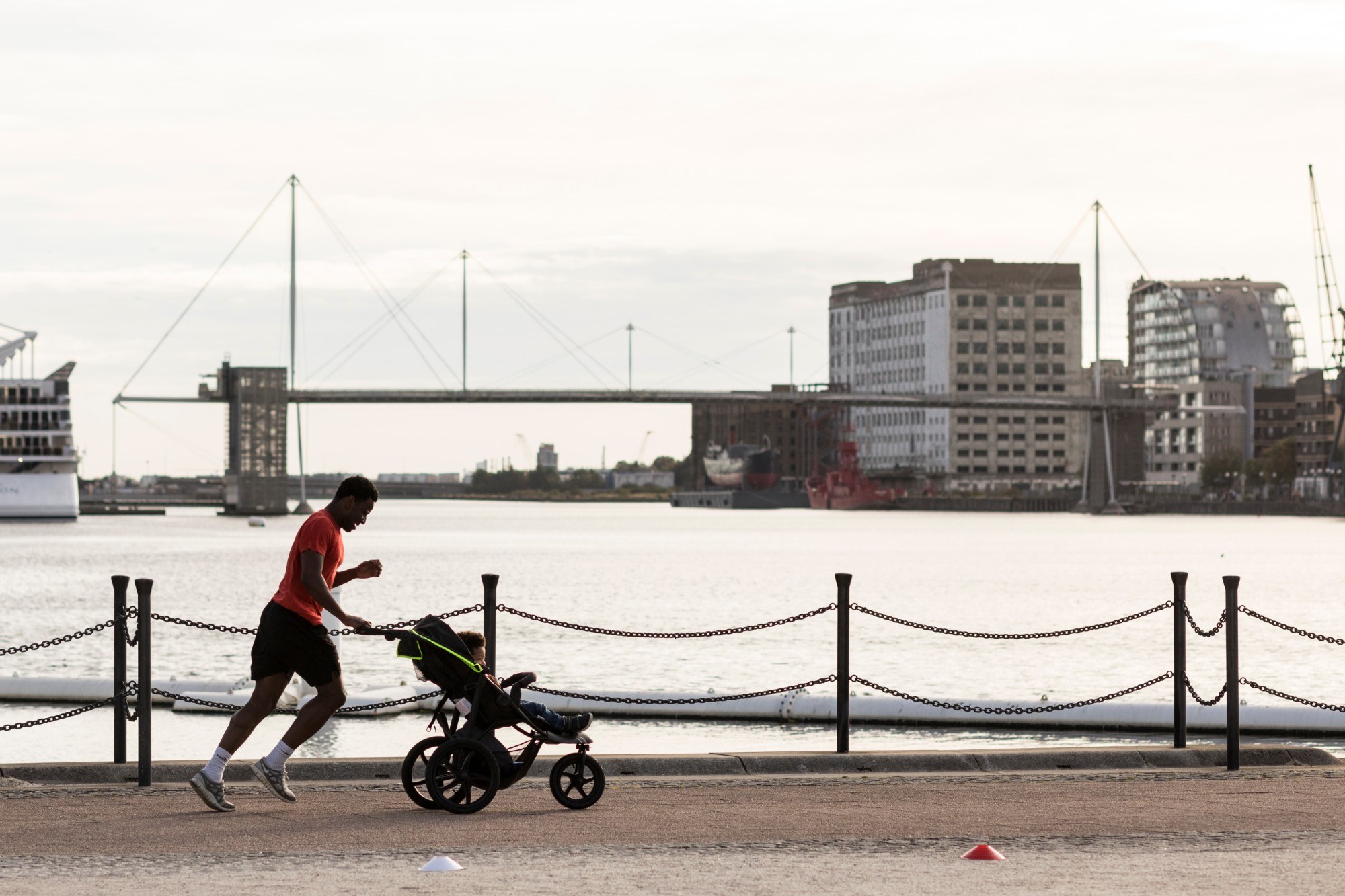 Man running along the edge of the dock with a buggy and a child