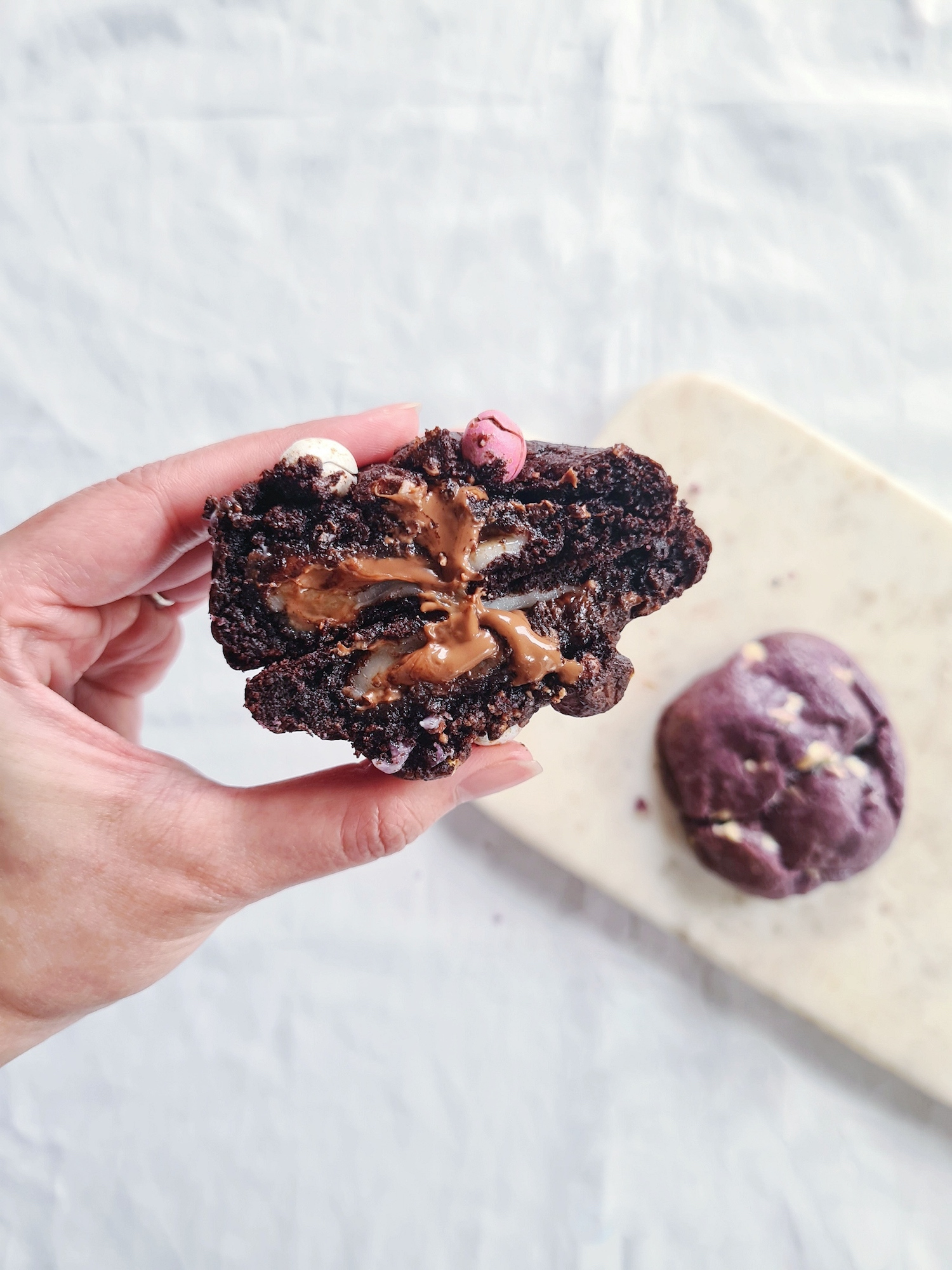 A cookie held up to show the gooey centre