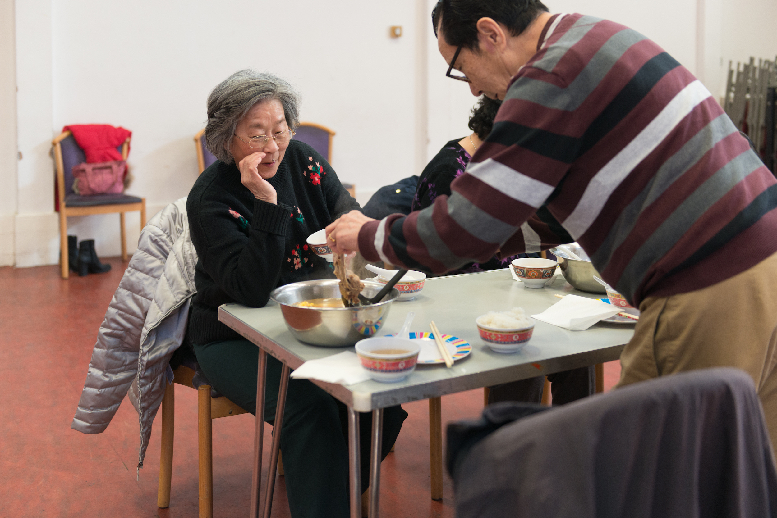 Man serving lunch, with two women sitting around a table