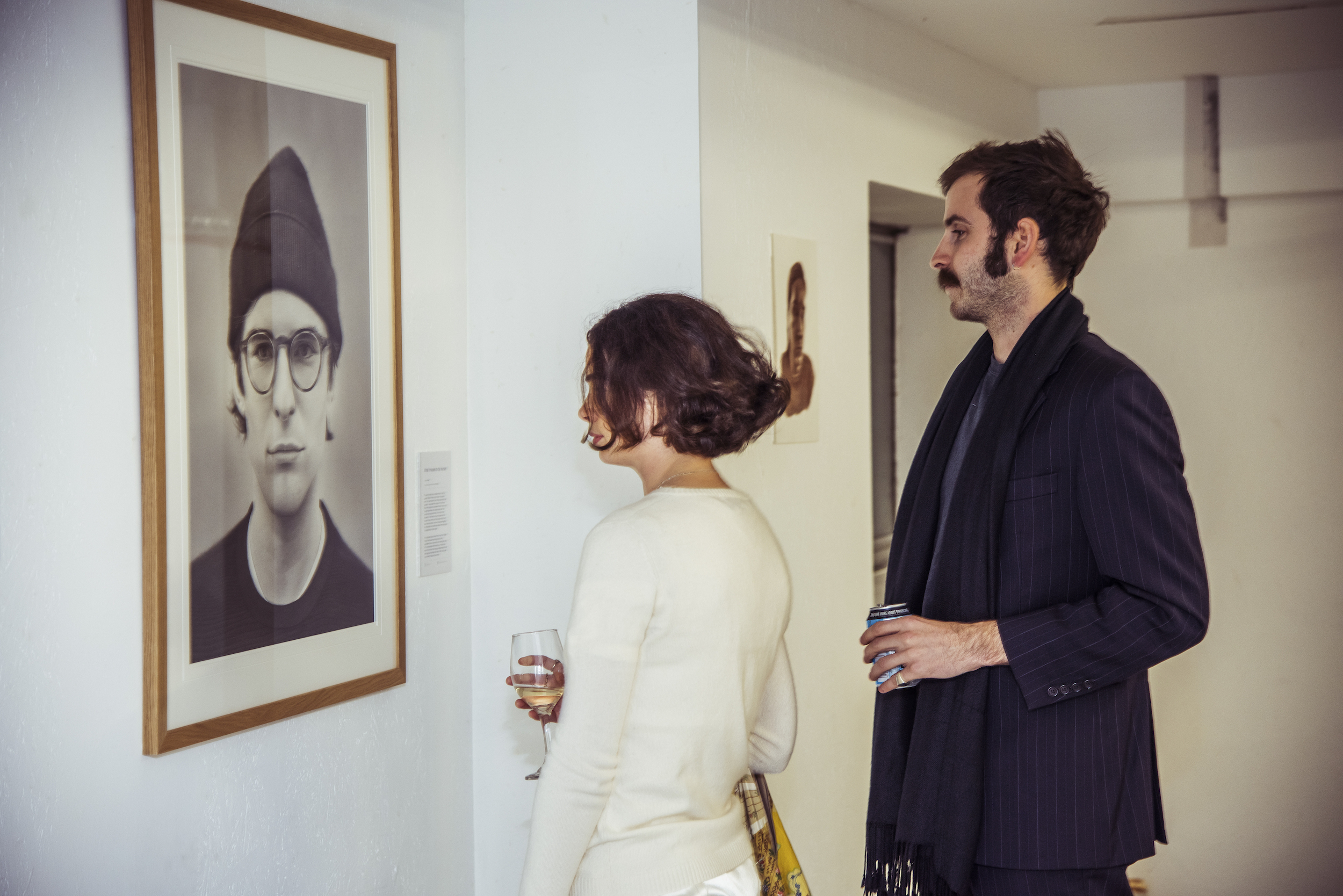 Two people looking at a photograph hanging on the wall