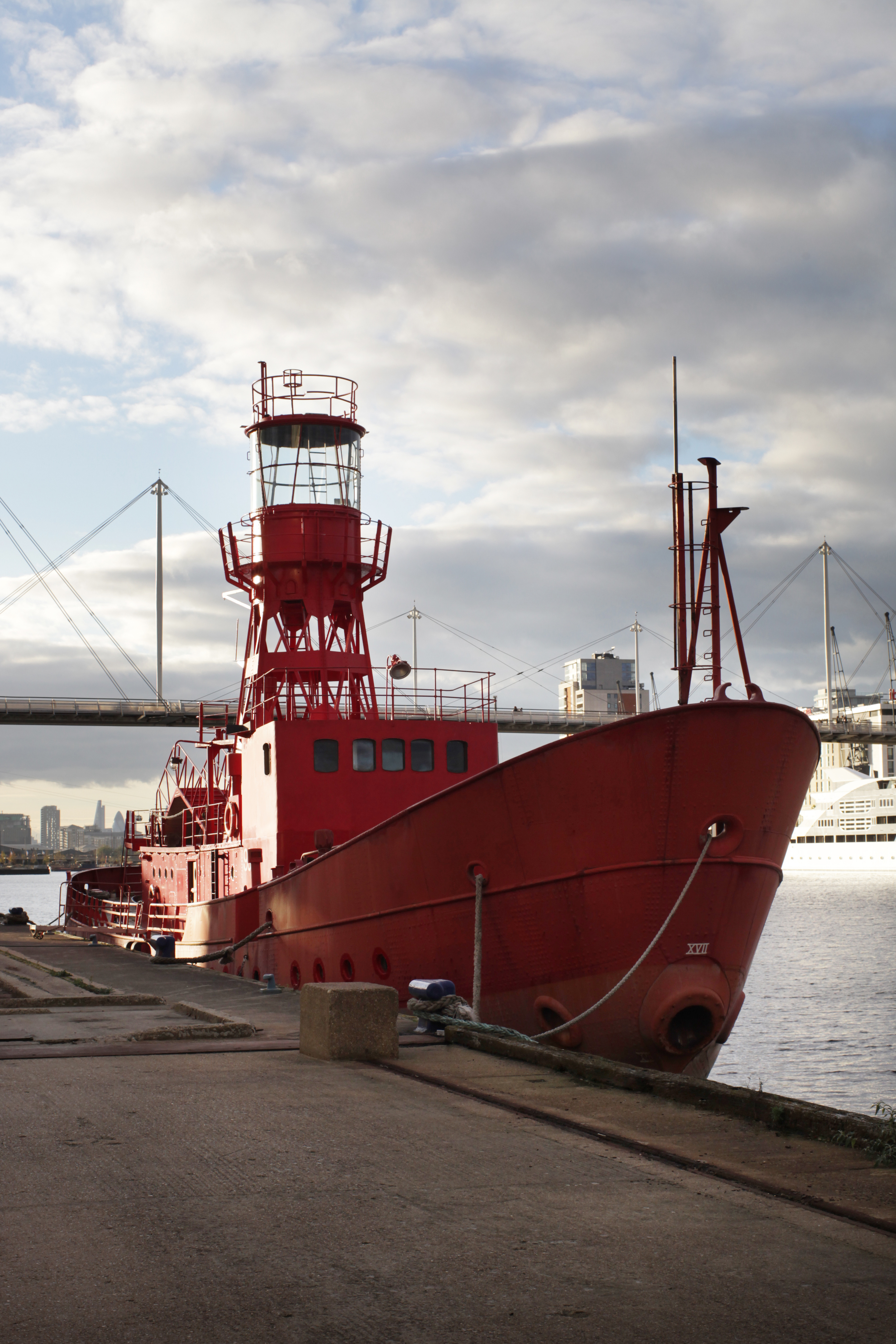 Red boat with lighthouse tower moored on the edge of the dock