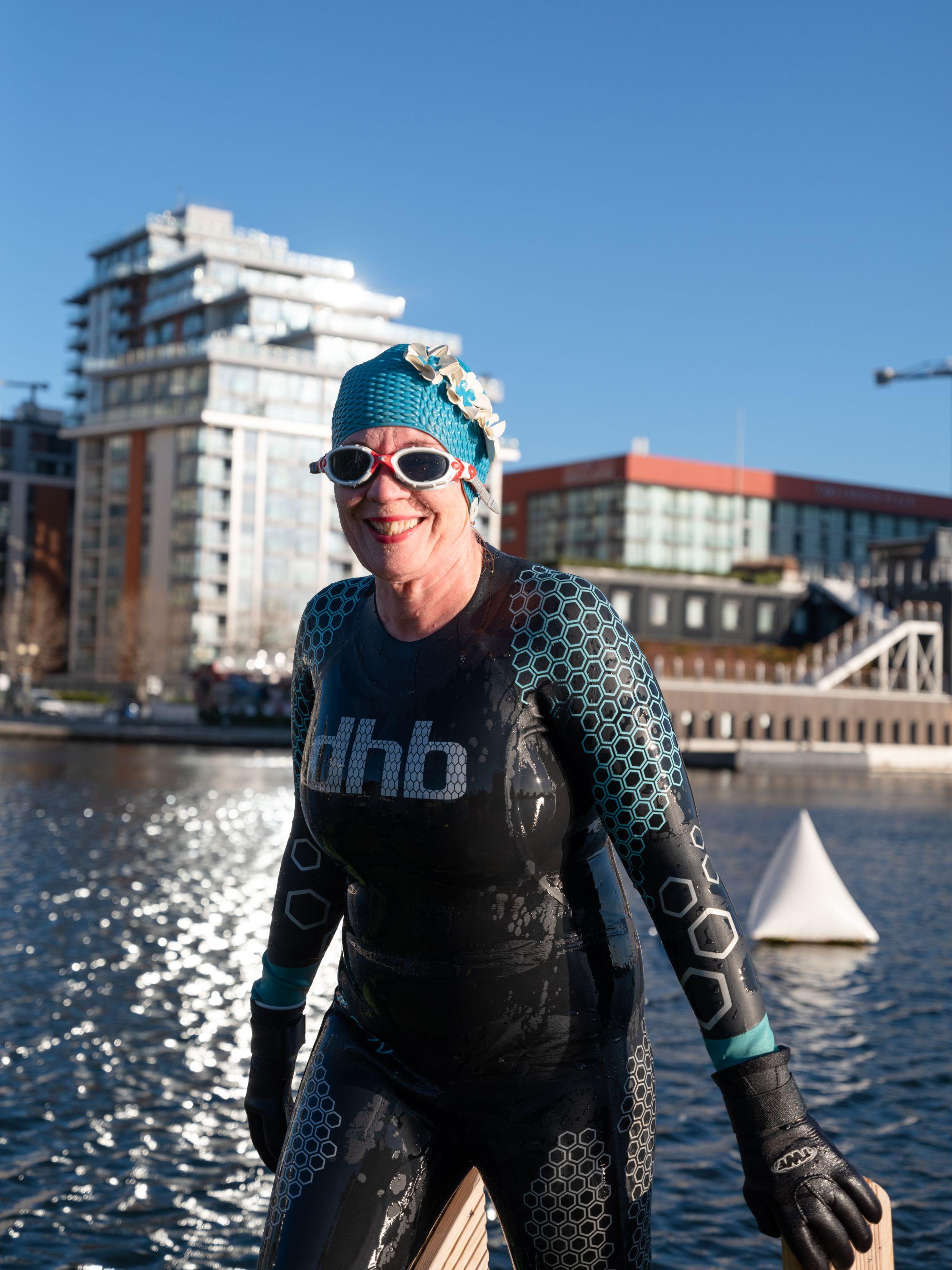 A swimmer emerges from the water, grinning widely