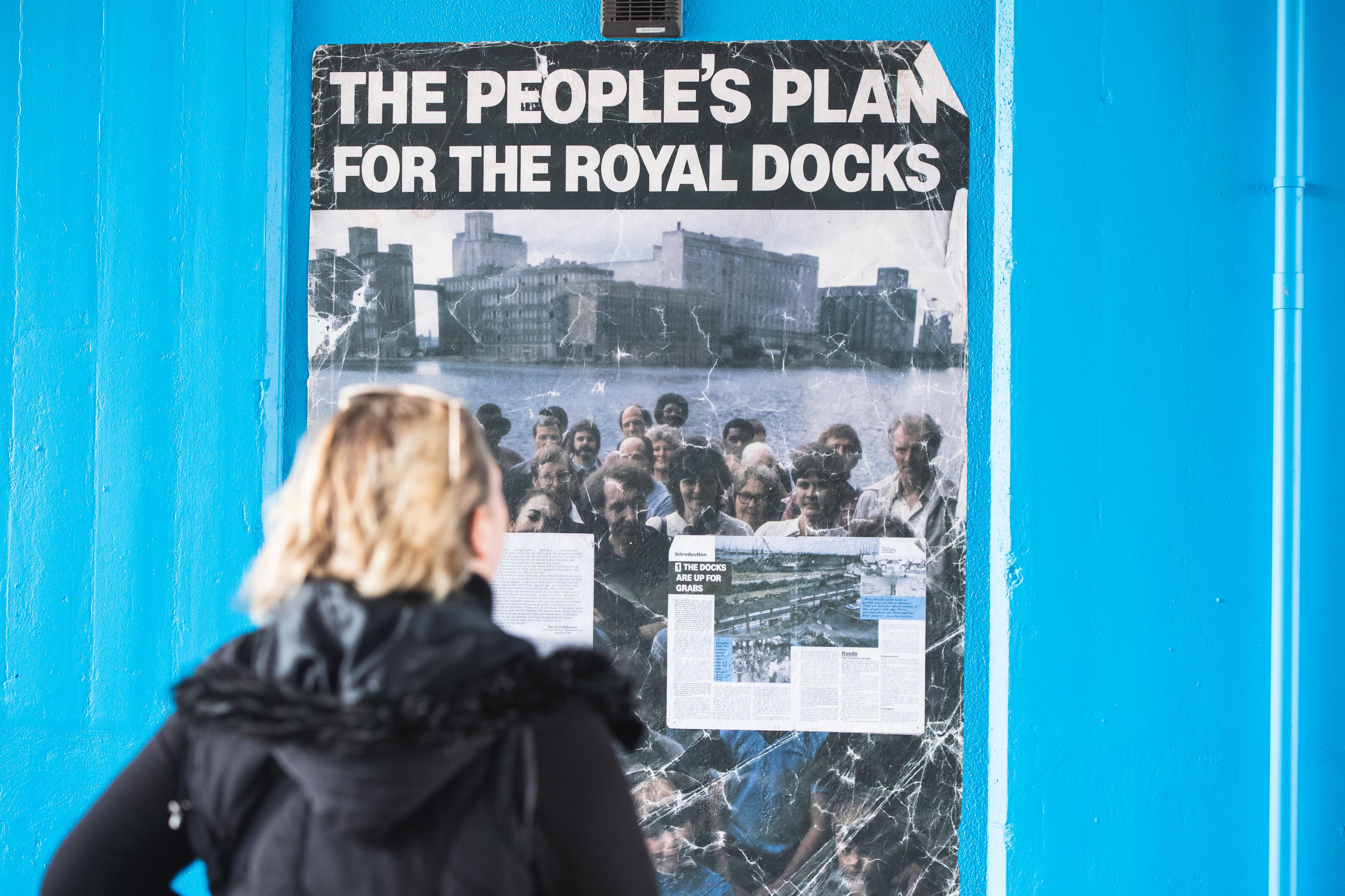 Blonde woman reads "the people's plan" poster