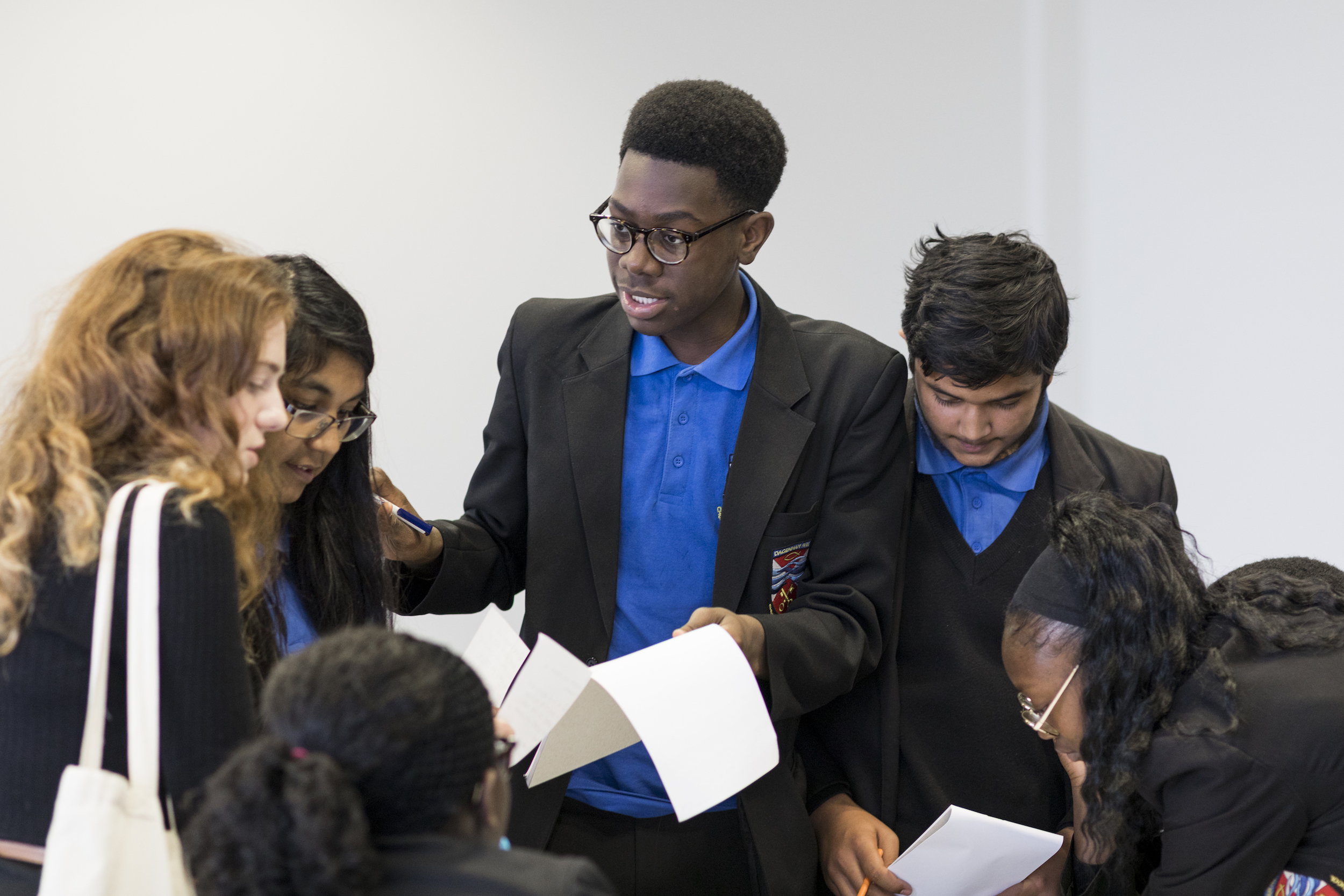 Children in discussion, holding pieces of paper