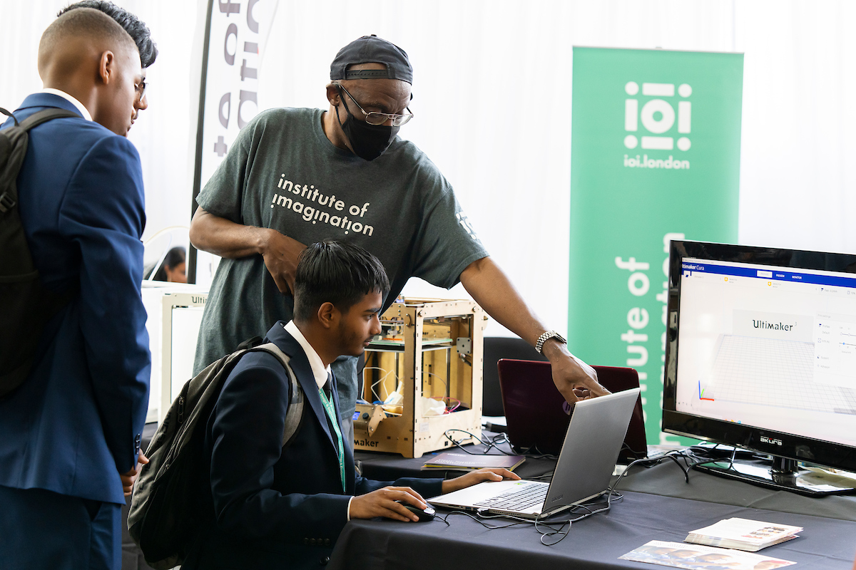 A schoolboy at a computer being instructed by a man from the Institute of Imagination