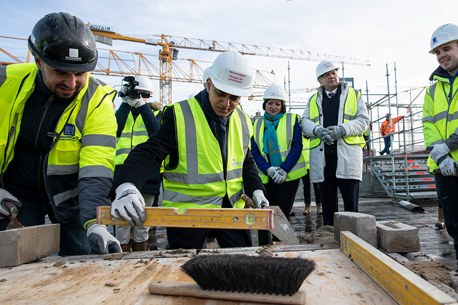 Mayor of London, Sadiq Khan at a topping out ceremony with five people in hi-viz safety gear.