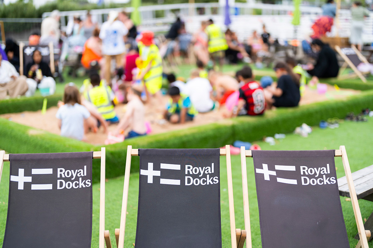 Three deckchairs in a row with the Royal Docks logo on