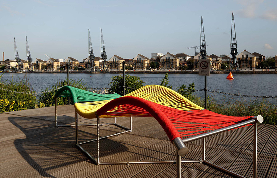 A green, yellow and red weaved bench in the Royal Docks.