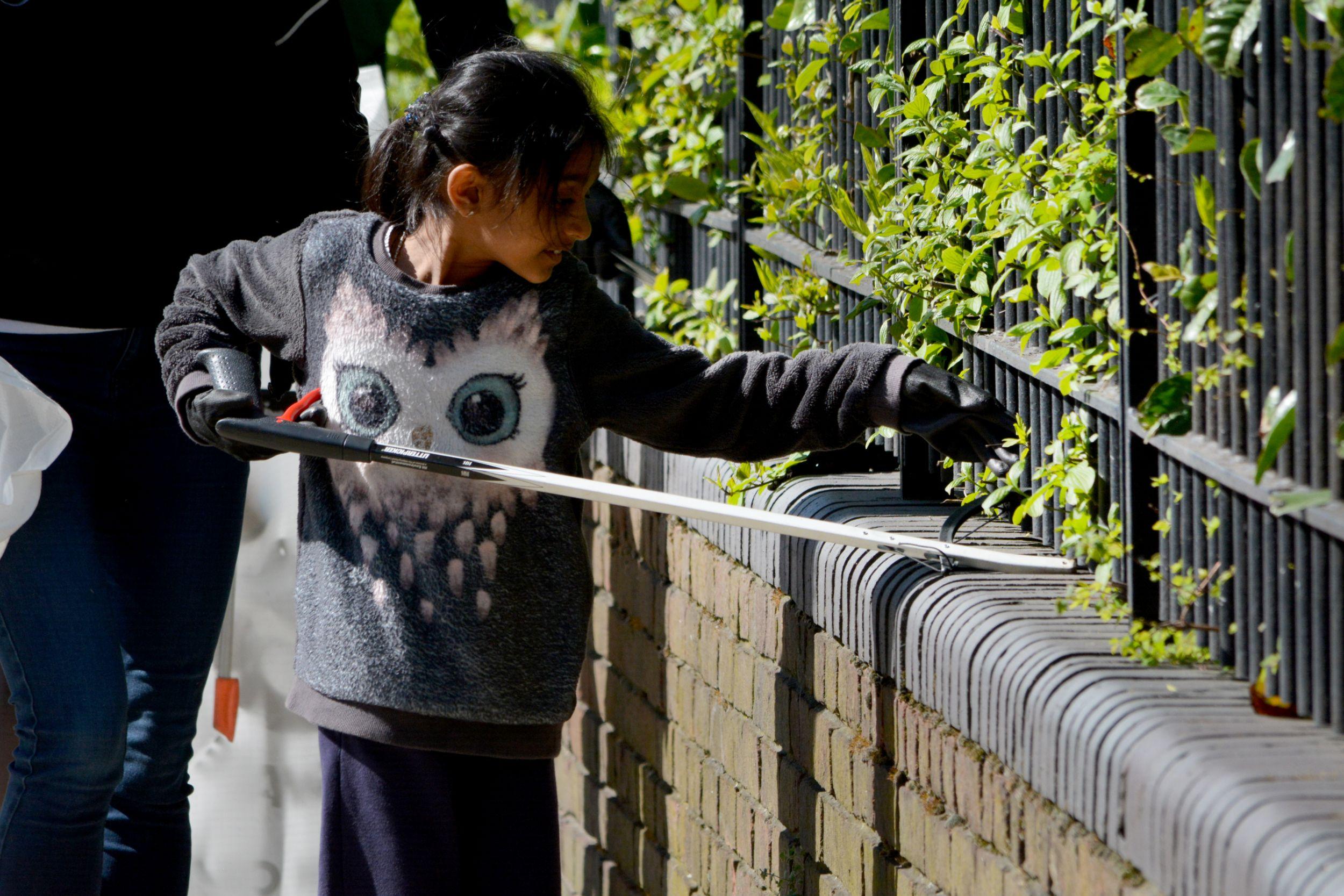 A girl searching for litter between railings
