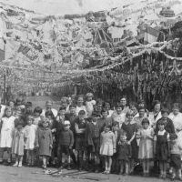 Historic photo of a street party with lots of bunting over the crowd