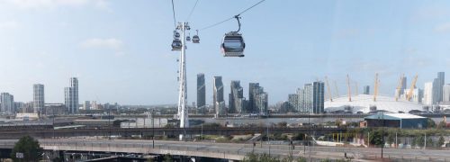 The cable cars flying over the Royal Docks with the Millennium Dome in the background