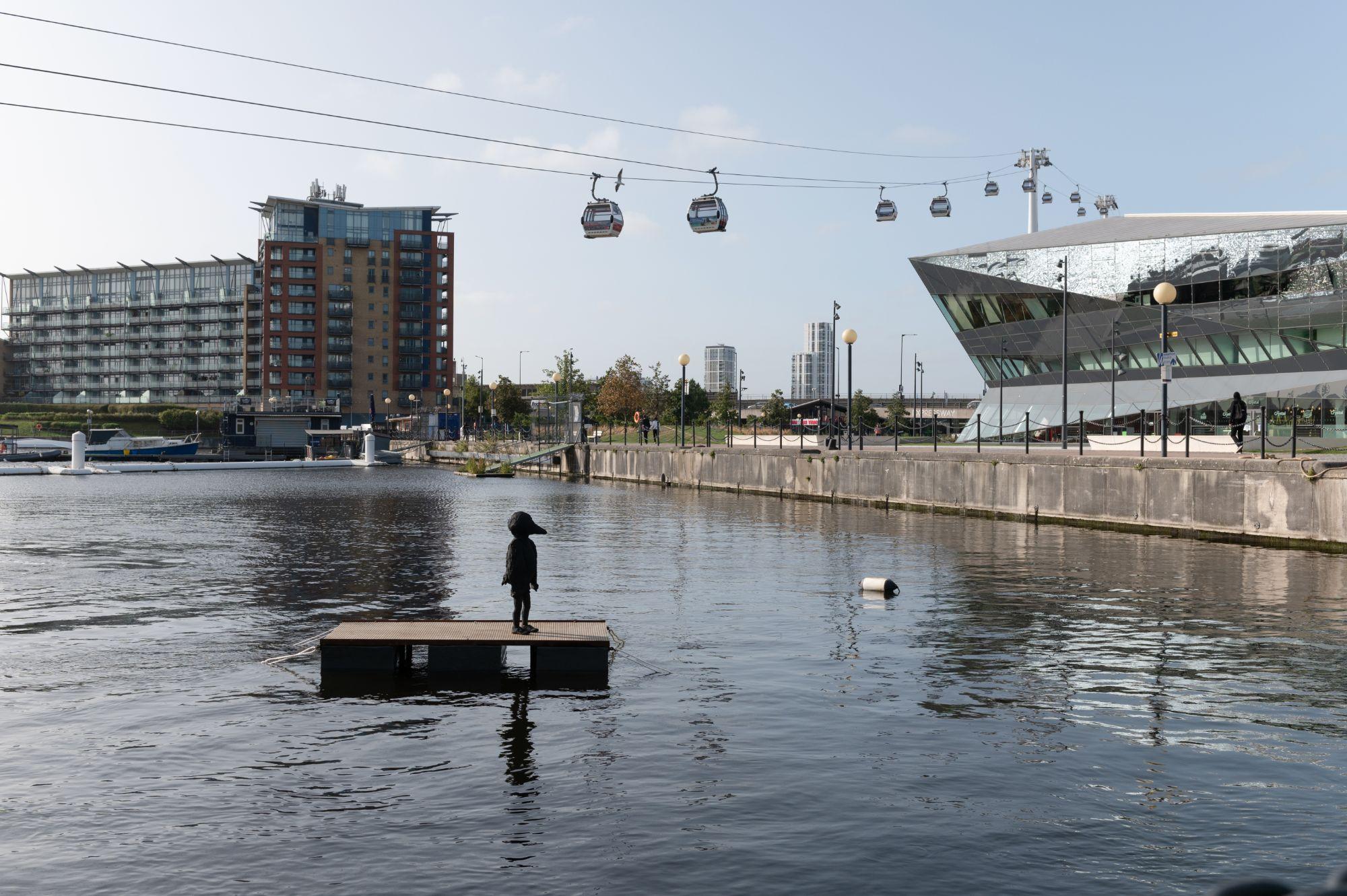 The cable cars over the dock water with the Bird Boy sculpture