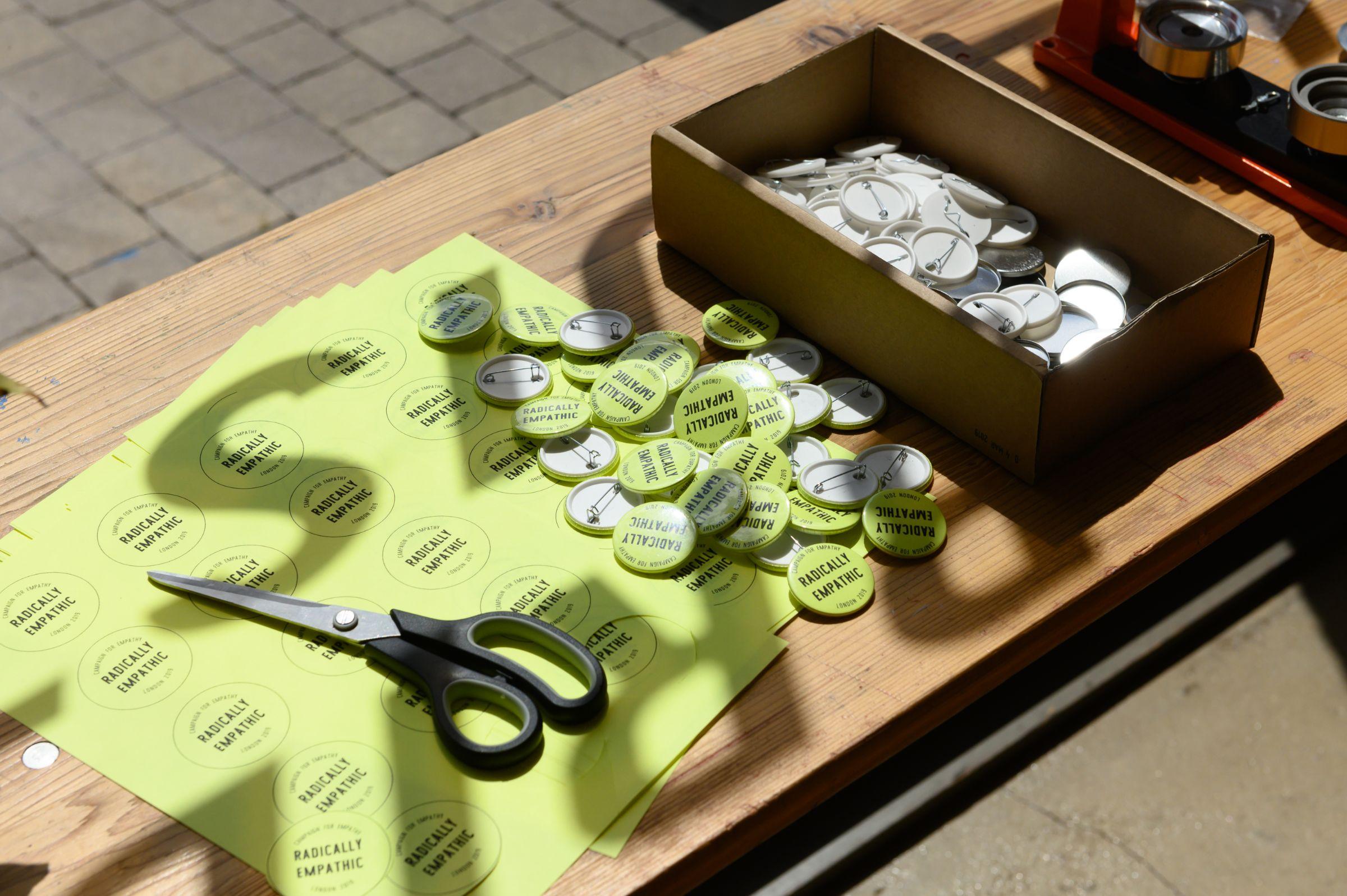 A table with badges and scissors on top of green paper