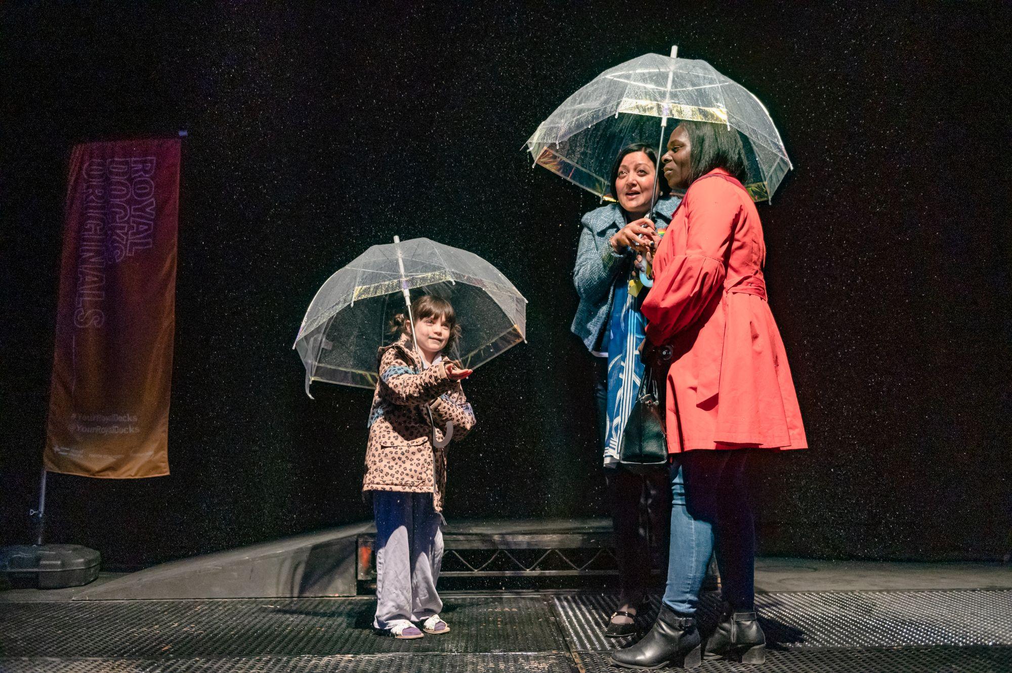 Two women and a little girl under umbrellas