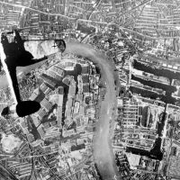 Old photo of a plane seen from above flying over the Thames