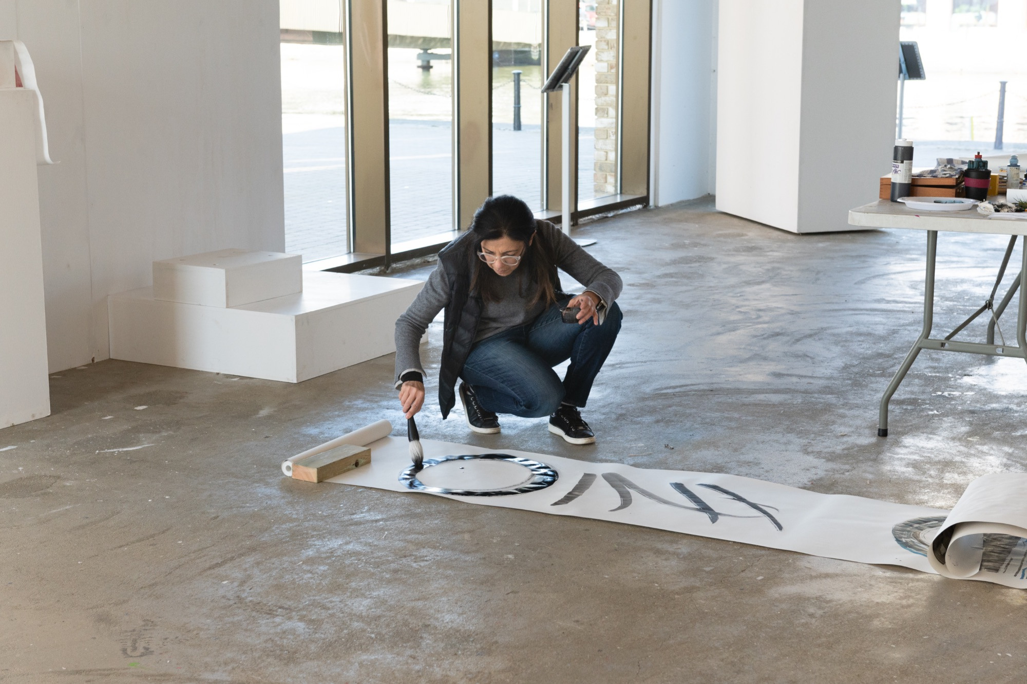 Artist bending over to work on a scroll on the floor