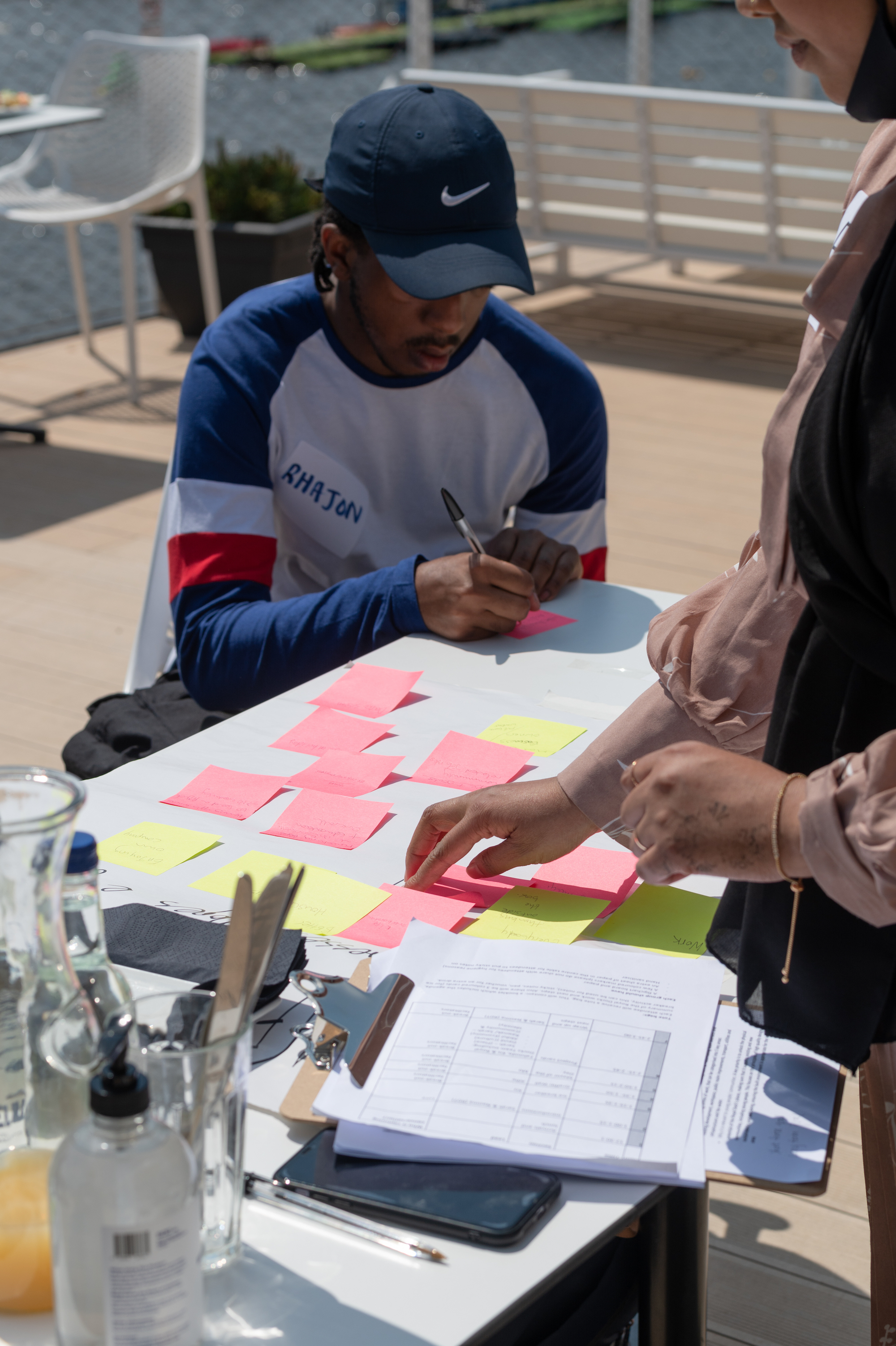 Young man in blue cap writing on postits during workshop