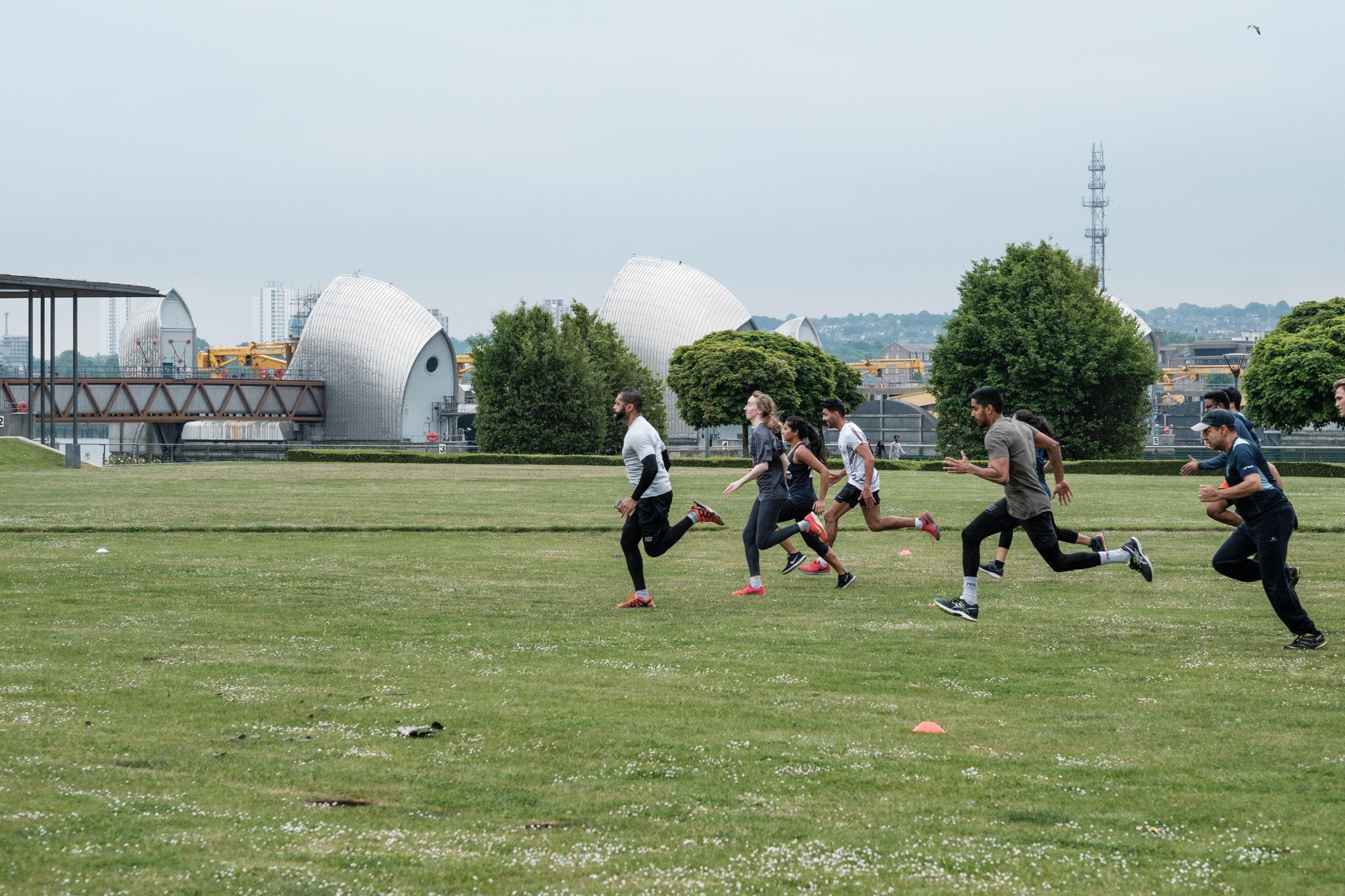 People sprinting across green space with Thames Barrier in the background