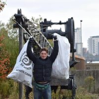 A man holds up two sacks of rubbish above his head