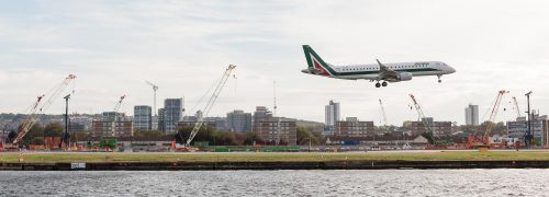 A plane above the runway, seen across the water