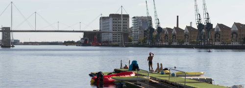 A man looking out into the Royal Docks water